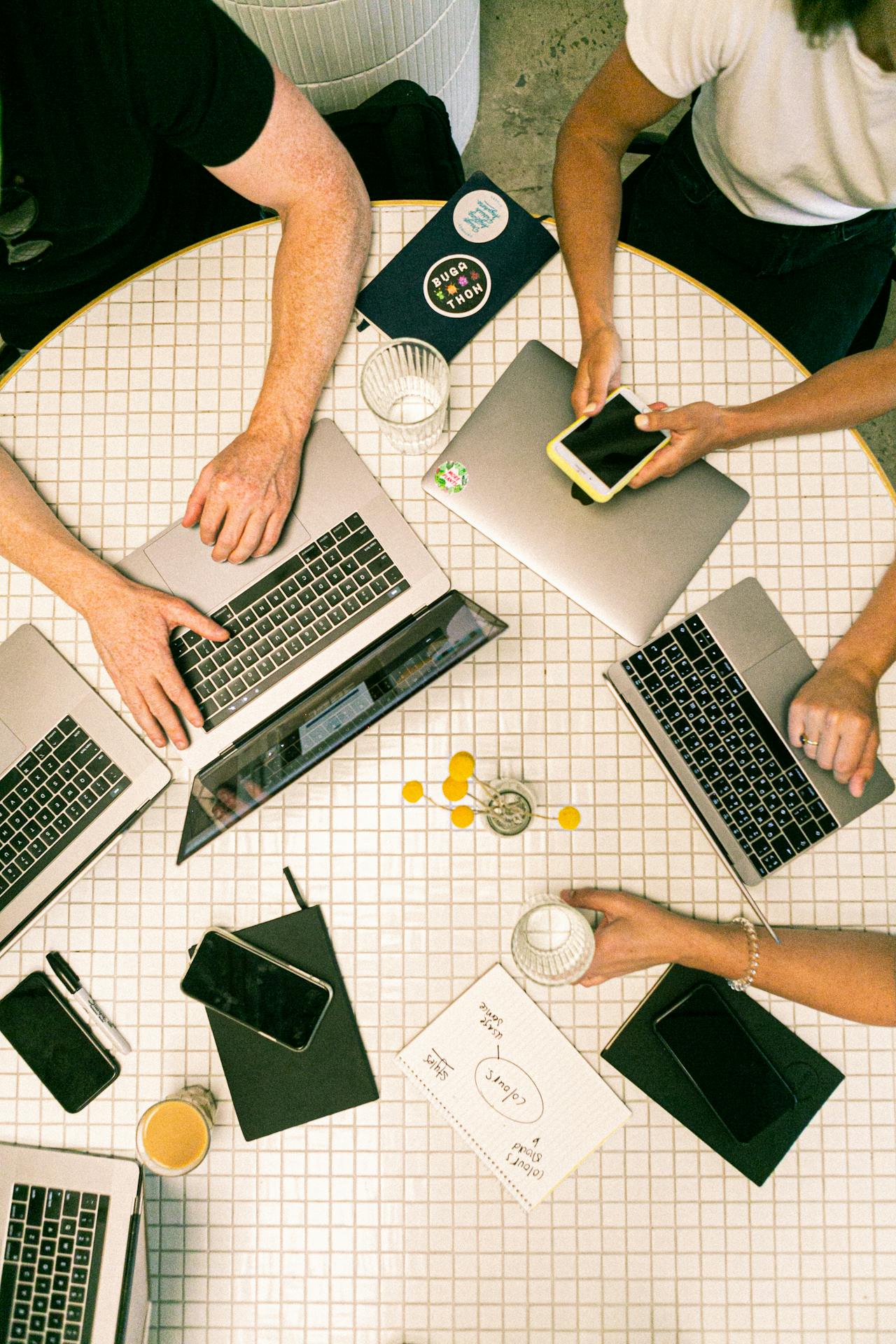 People sitting around table with laptops and mobiles